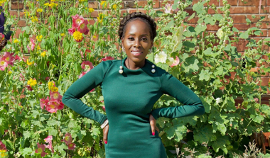 Andile Pfupa, creator of Bee You Kids posing in front of tall flowering plants