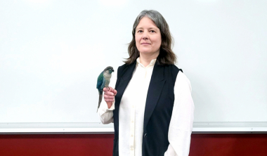 Jessie with her Green-cheeked Conure, Sapphire perched on her finger